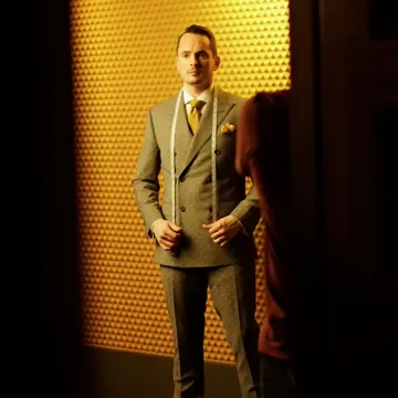 A client in a double-breasted suit with a measuring tape around his neck