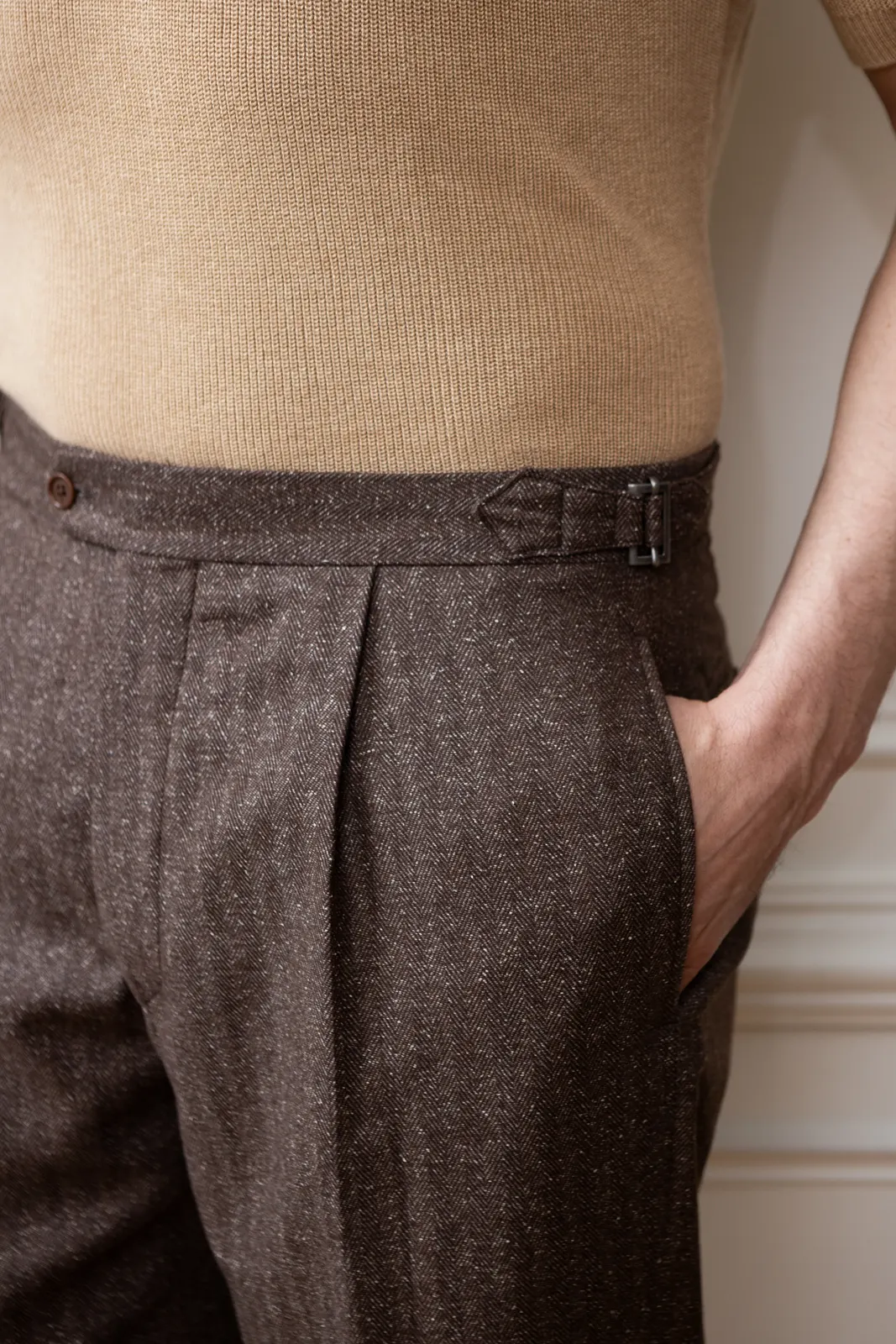 The waist of brown tweed trousers with a front pleat