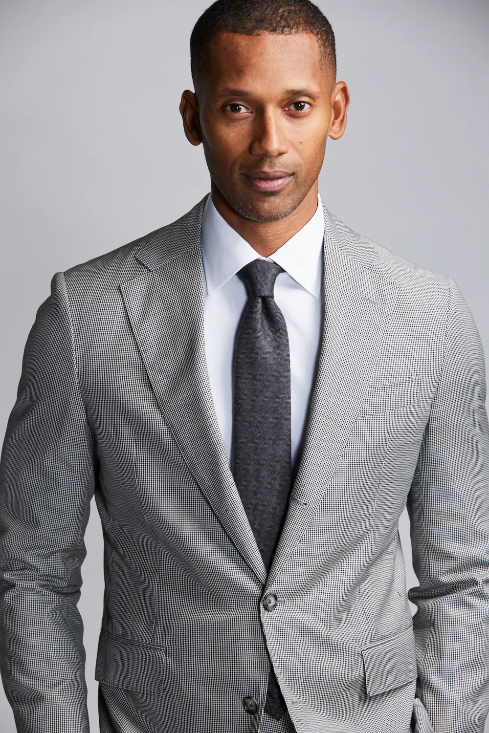 A gray houndstooth suit jacket worn with a white shirt and dark tie