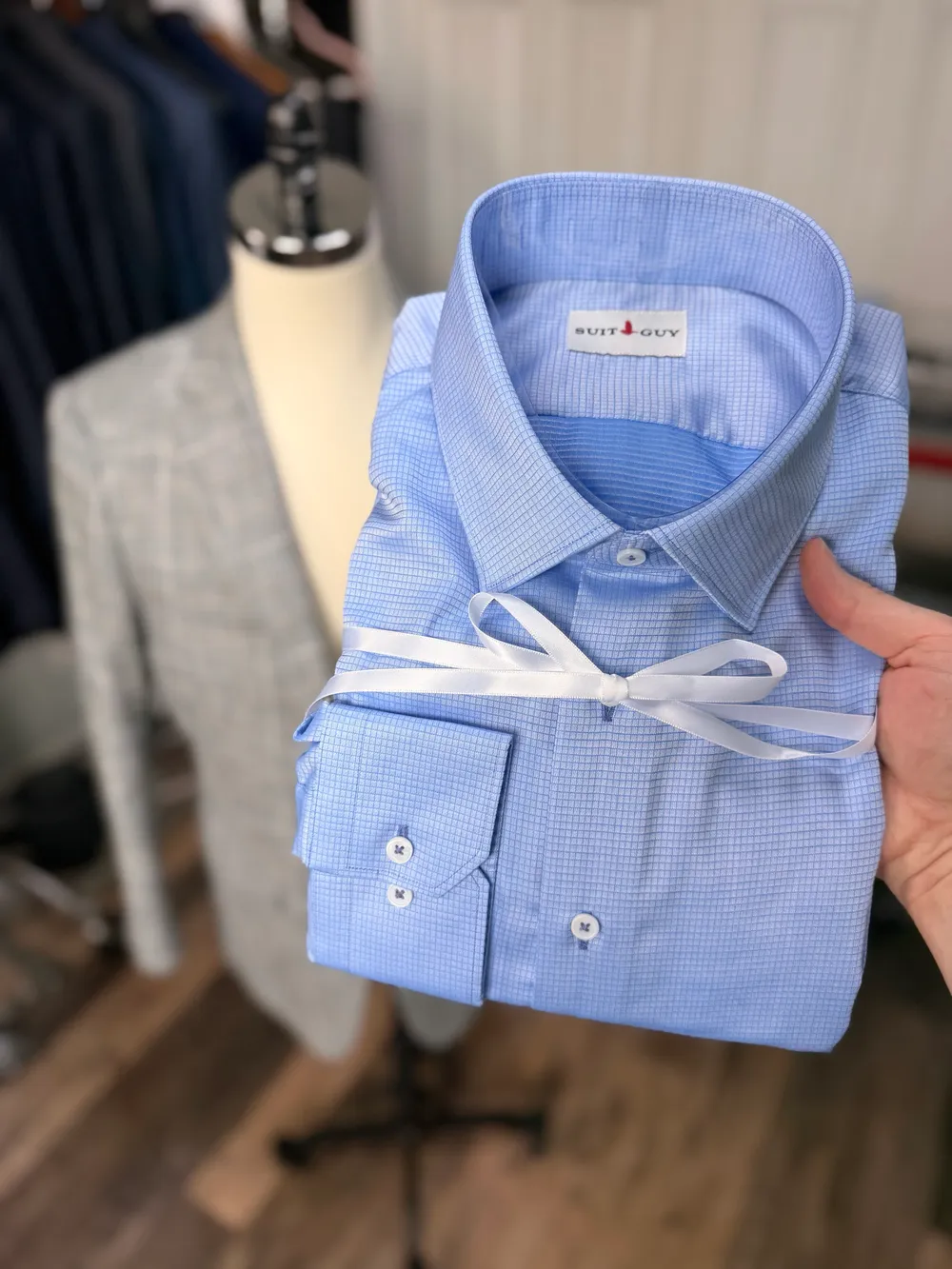 A blue check shirt folded and tied with white ribbon