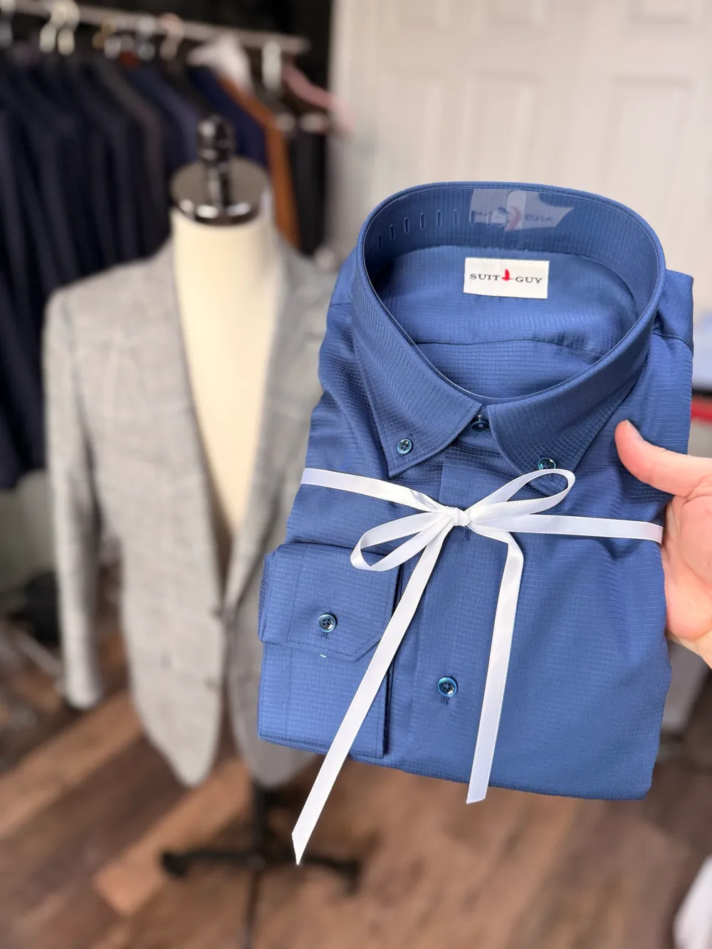 A navy textured shirt folded and tied with white ribbon