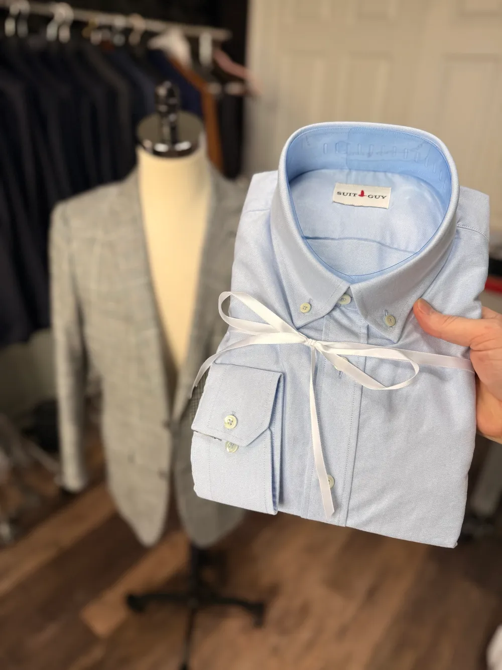 A light blue button-down oxford shirt folded and tied with white ribbon