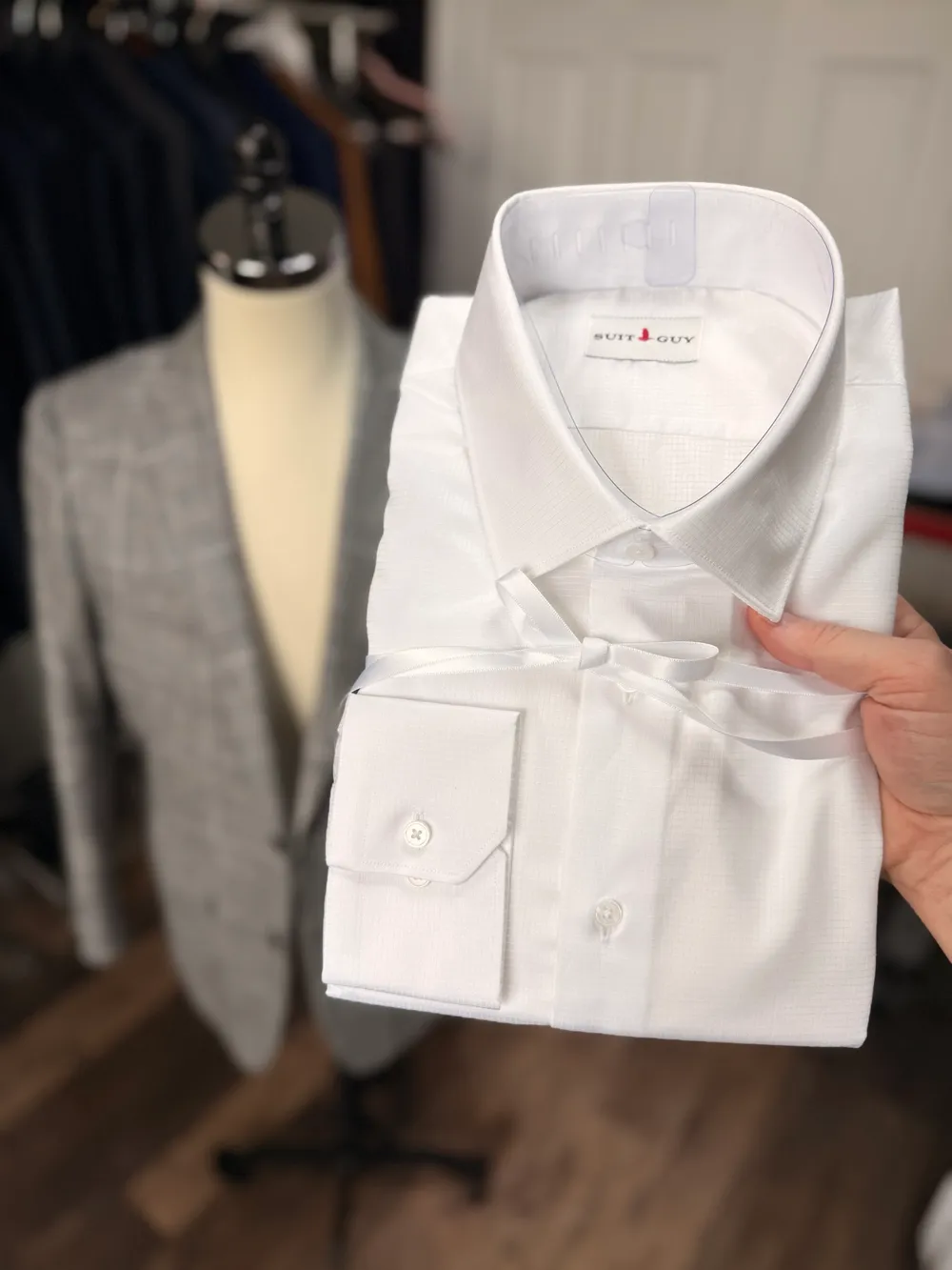 A white textured shirt folded and tied with white ribbon