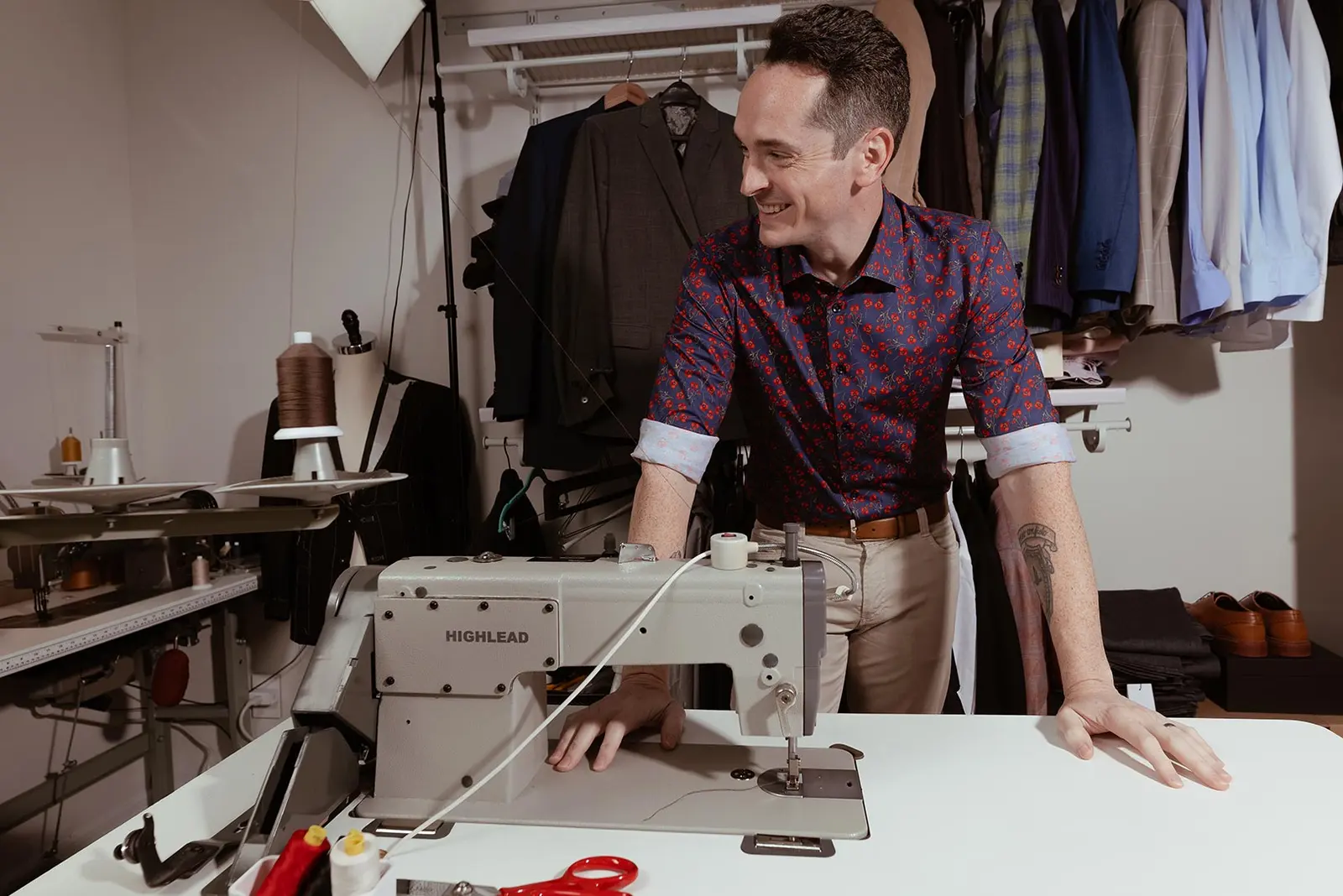 Aaron McGill smiling at his sewing machine in the studio