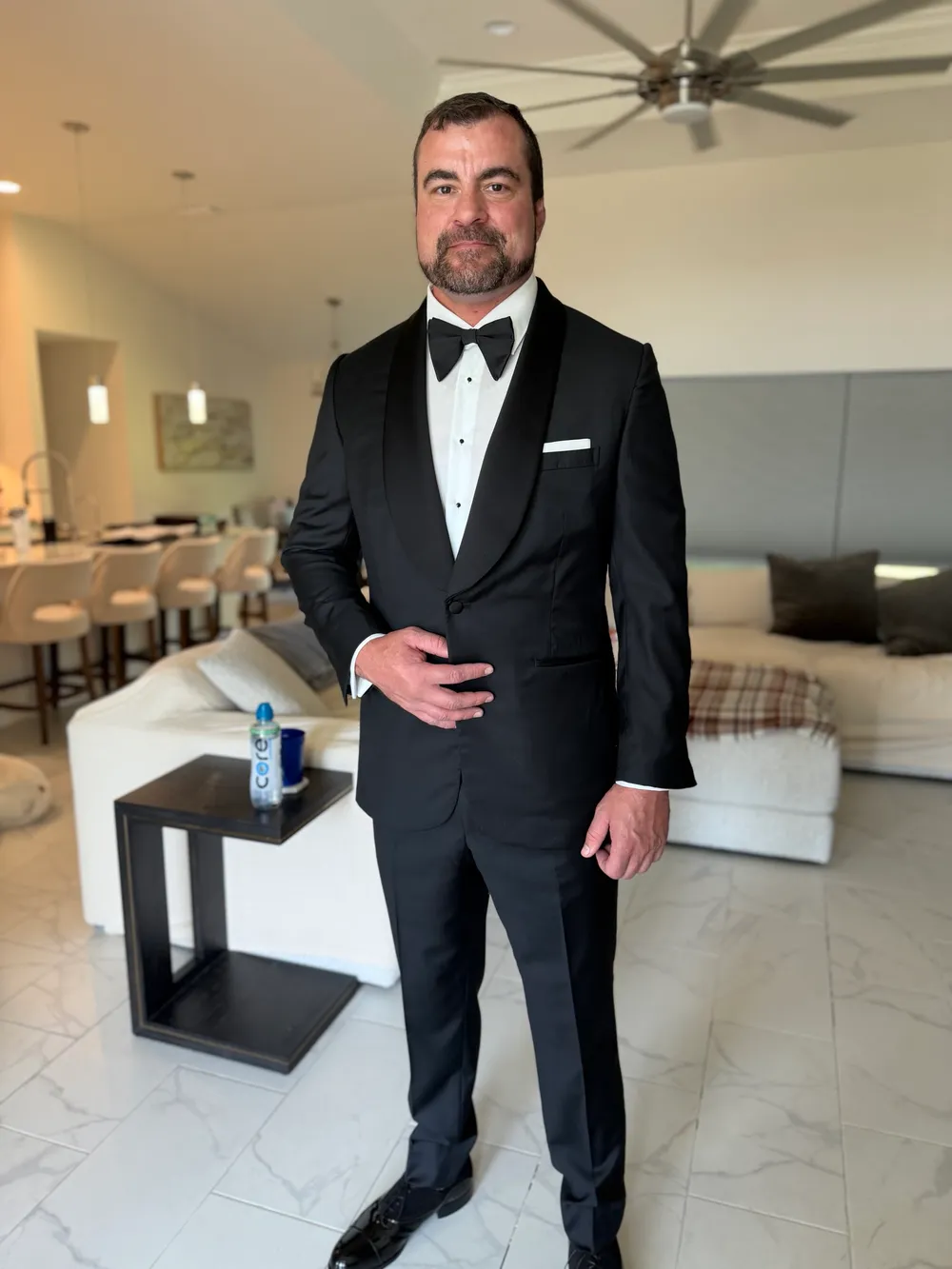 A man in a custom shawl-collar tuxedo with a one-button jacket, bow tie and white pocket square