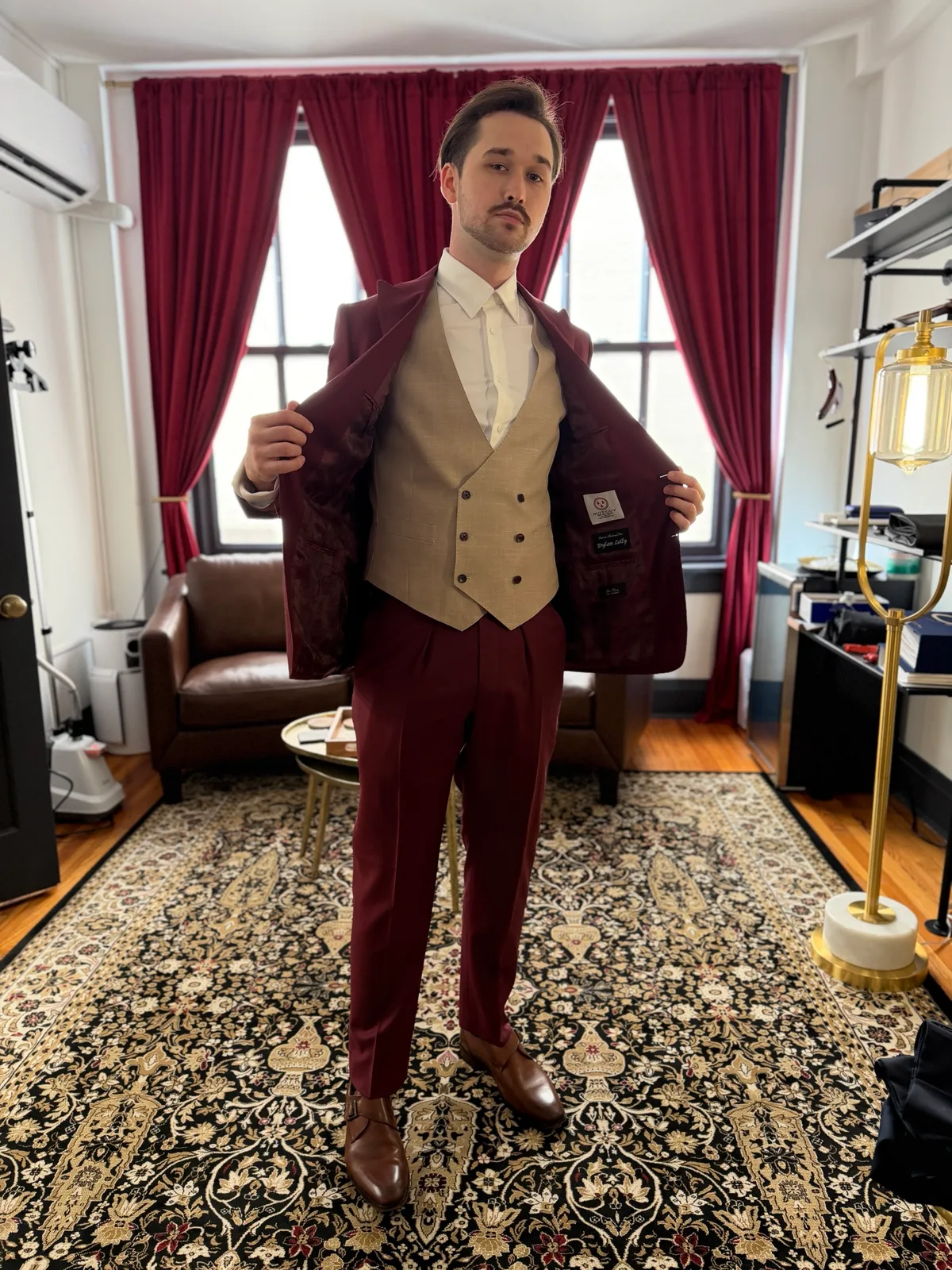 A burgundy jacket held open to show the lining and a tan double-breasted vest