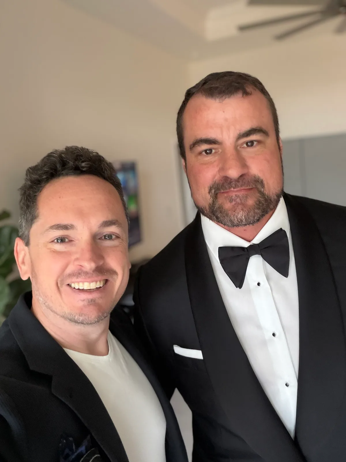 Aaron McGill with a groom in a custom black shawl-collar tuxedo, white shirt with studs, bow tie and white pocket square