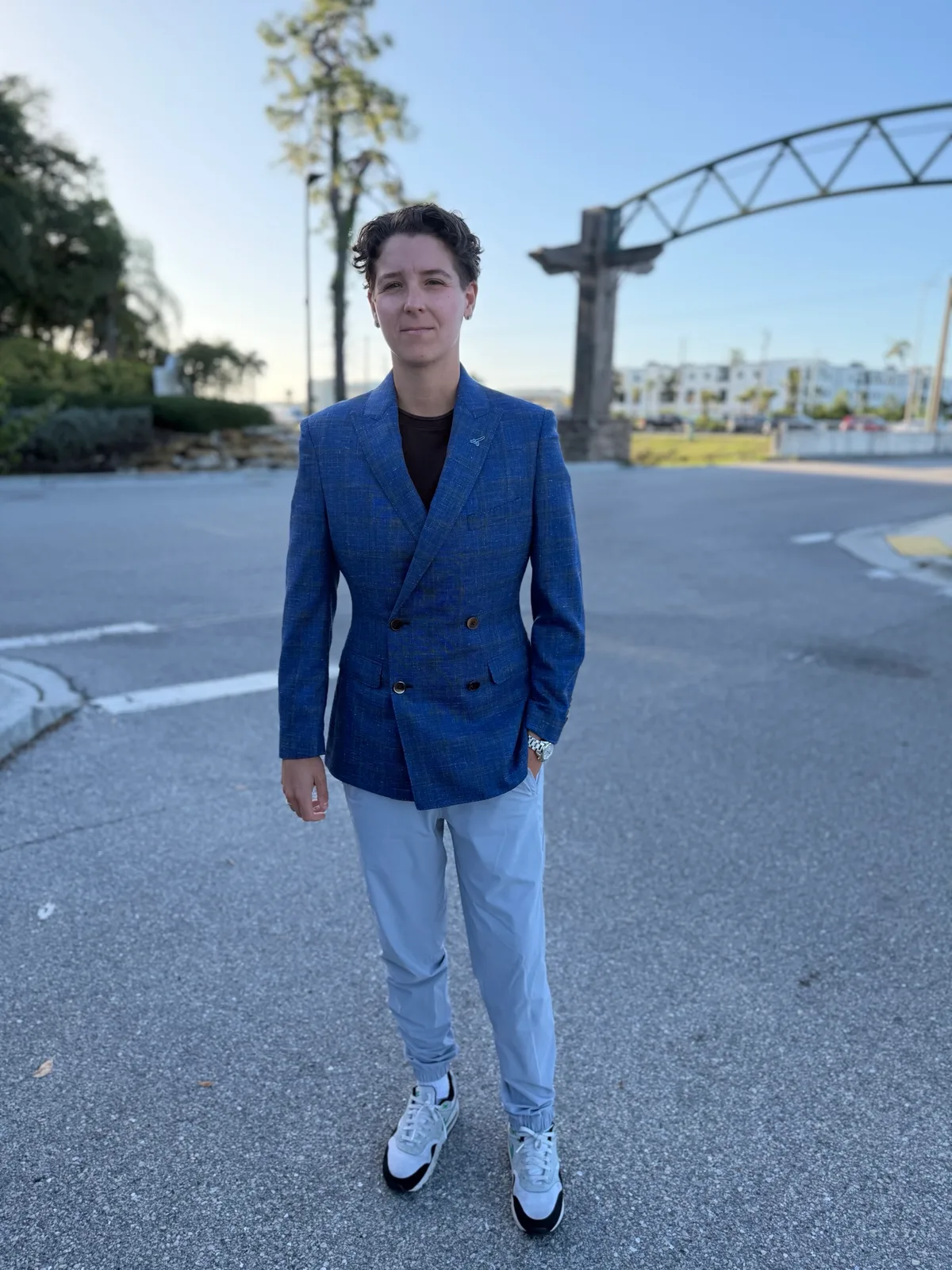 The same blue double-breasted blazer worn outdoors with light blue trousers and sneakers