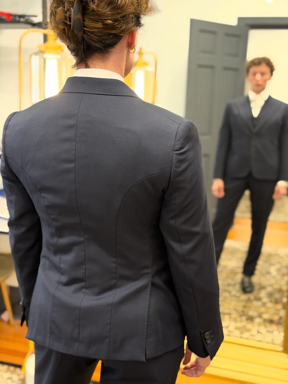 The back of a custom navy jacket, with the three-piece suit reflected in the mirror