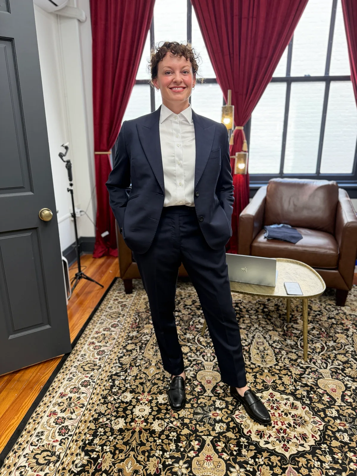 A woman in a custom navy suit with a peak-lapel jacket, white shirt and black loafers